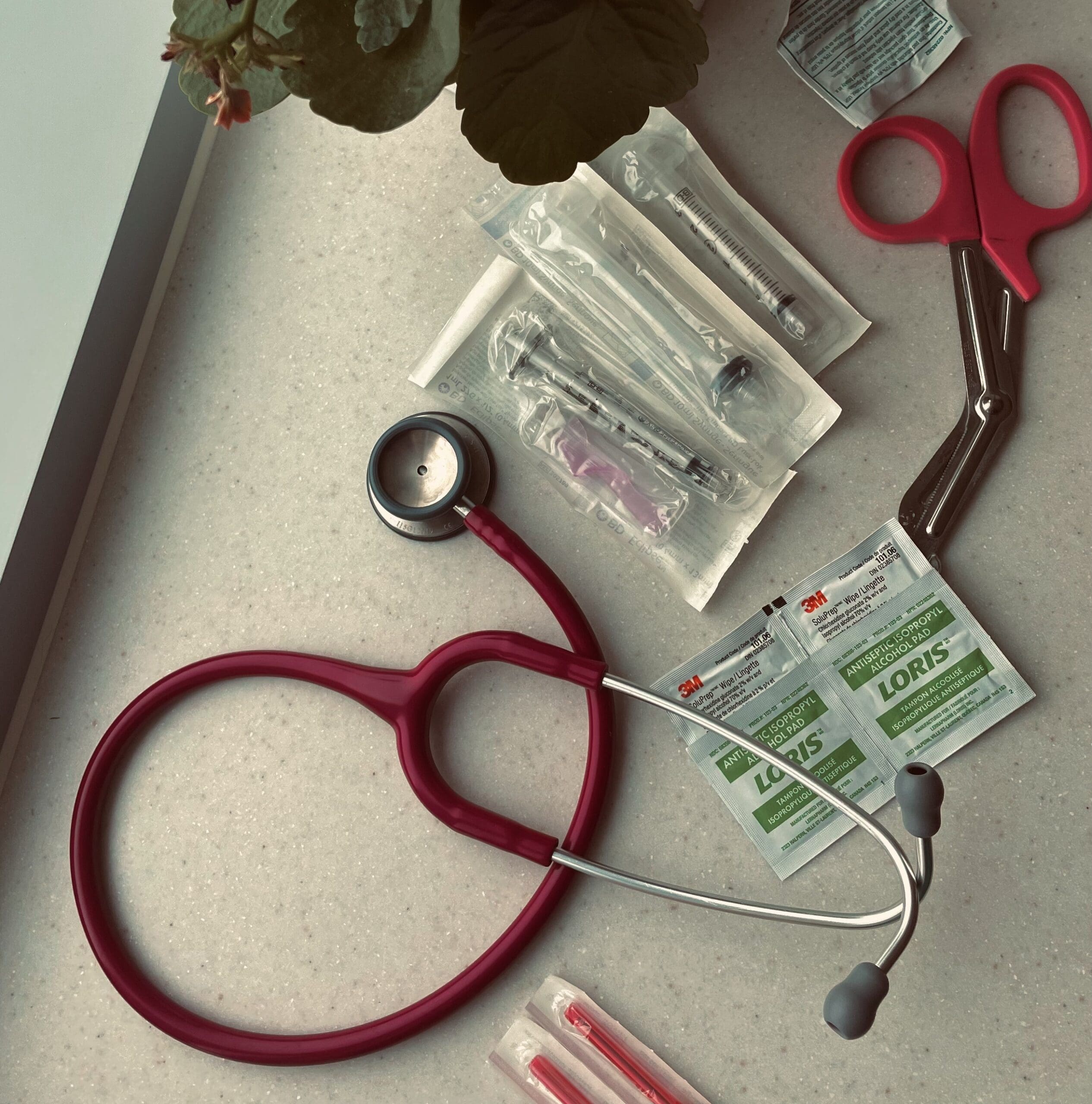 Overlay of items nurses use on a given shift--stethoscope, scissors, alcohol swabs, syringes, and blunt needles.